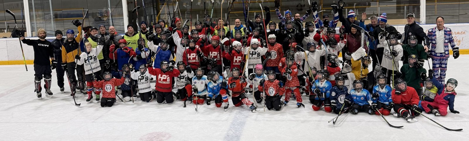 Gruppenfoto der EC Wels Juniors mit Trainern und Eltern auf dem Eis der Eishalle Wels