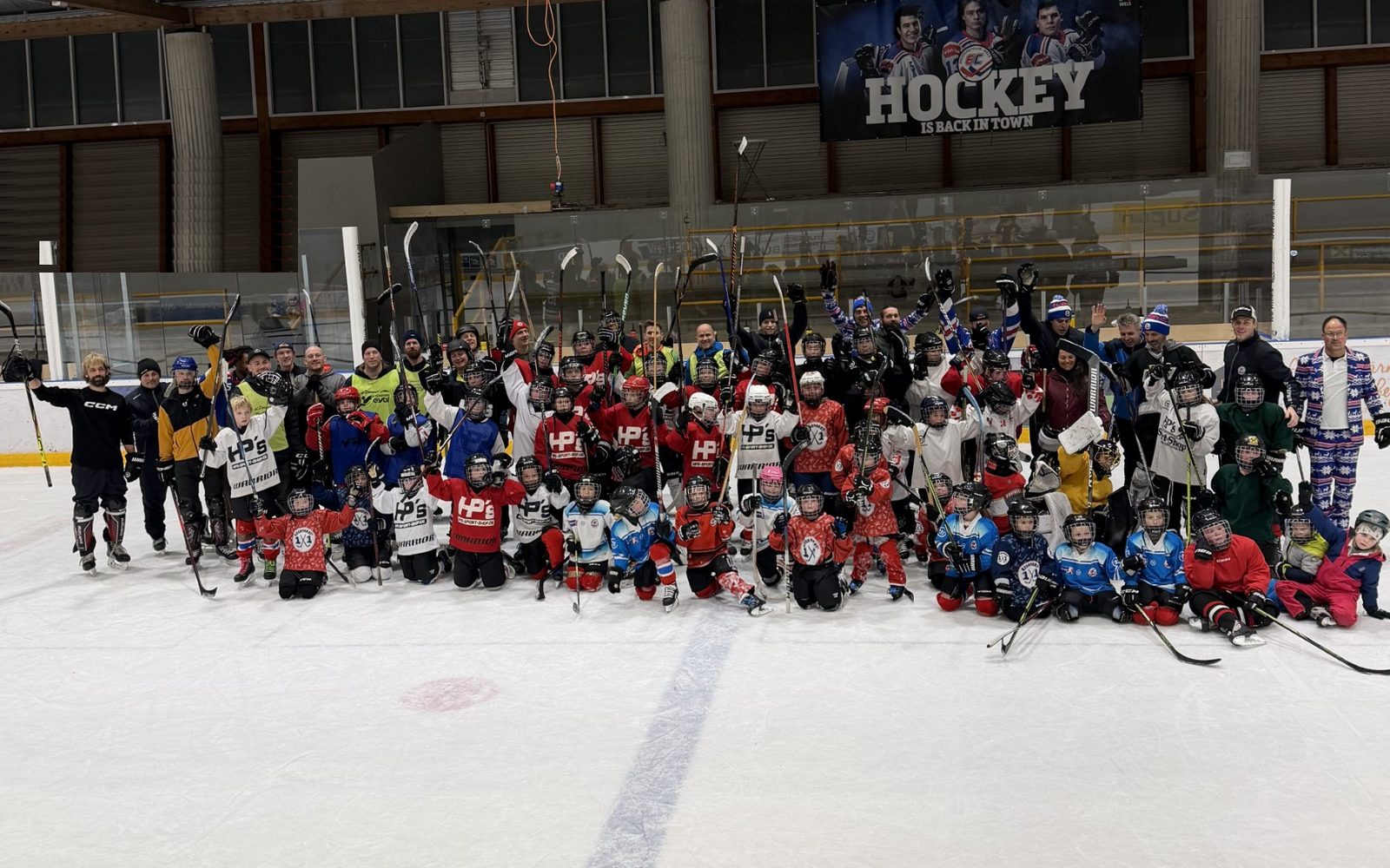 Gruppenfoto der EC Wels Juniors mit Trainern und Eltern auf dem Eis der Eishalle Wels